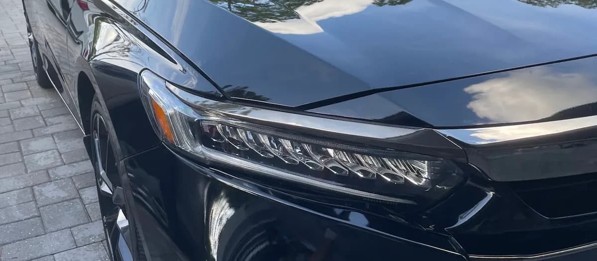Glossy black sedan with mirror-like paint finish after waxing and polishing by Sansanich Car Detailing in North Port, FL
